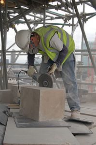 A stonemason makes the initial cut into a block of stone which will eventually be fixed and shaped to match the curved profile of the surrounding stone